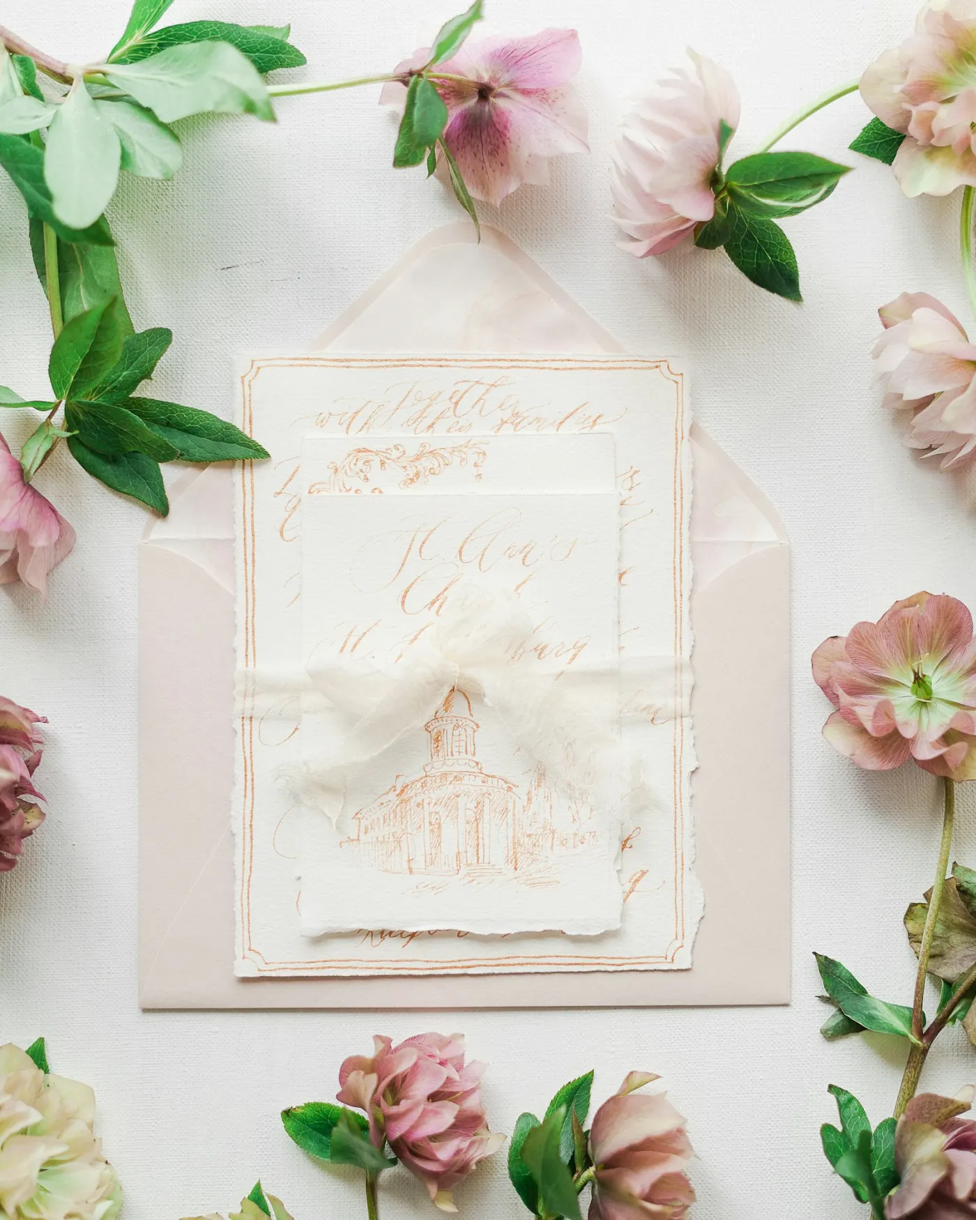 A flat-lay of a printed wedding invitation suite, including the invitation, save-the-date, and RSVP cards.